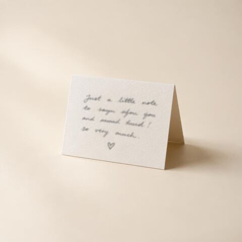 A small folded handwritten note card with a drawn heart